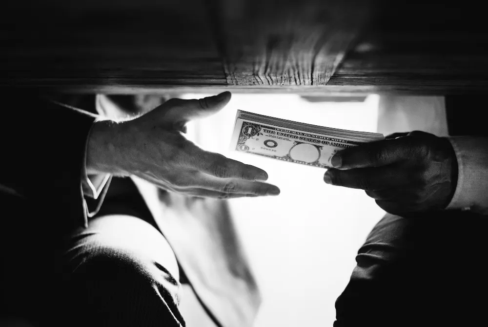 hands-passing-money-table-corruption-bribery